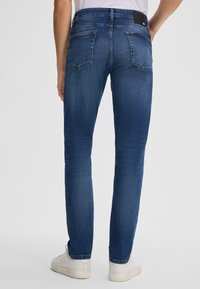 Granatowe dżinsy o prostym kroju, z dwiema tylnymi kieszeniami i delikatnym wyblaskiem. Wykończone białymi sneakersami.