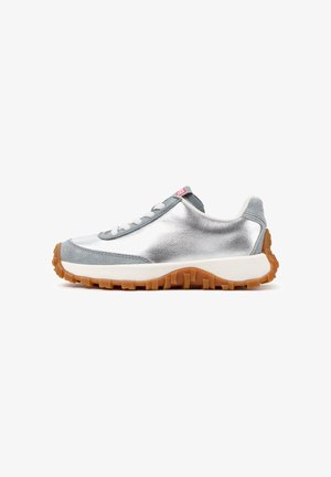 Sidevisning af en sølv- og grå sneaker med hvide snørebånd, en tyk hvid mellemsål og en brun gummiydersål med mønster.