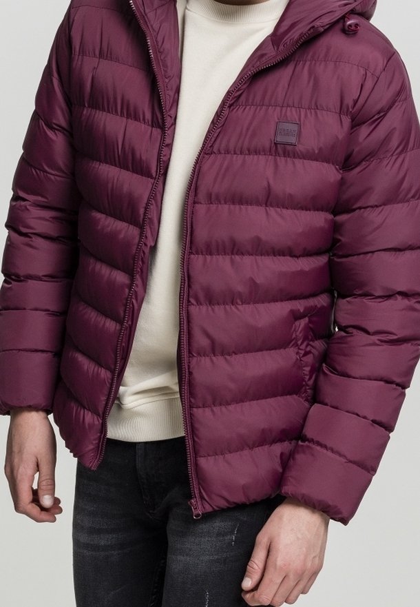 Burgundowa kurtka puchowa z poziomym pikowanym wzorem, z przodem na zamek błyskawiczny, odczepianym kapturem i kieszeniami bocznymi, noszona na kremowym swetrze.