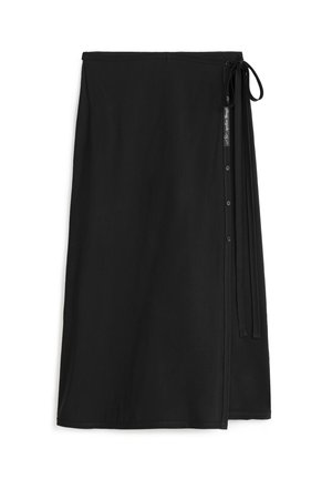 Falda envolvente negra hecha de una tela suave, con un cierre de lazo en el costado y un detalle de botones en la parte delantera.