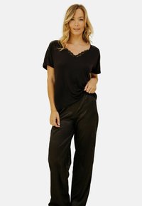 T-shirt noir à col V accentué de dentelle, associé à un pantalon noir texturé à coupe ample. Les deux vêtements ont une coupe décontractée et un tissu doux.