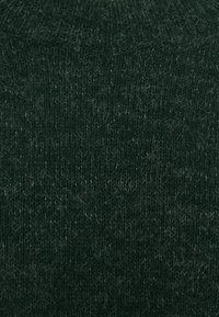 Tissu de pull en maille de couleur vert foncé avec une surface douce et texturée. Présente des fibres visibles et un léger éclat, créant une apparence douillette.