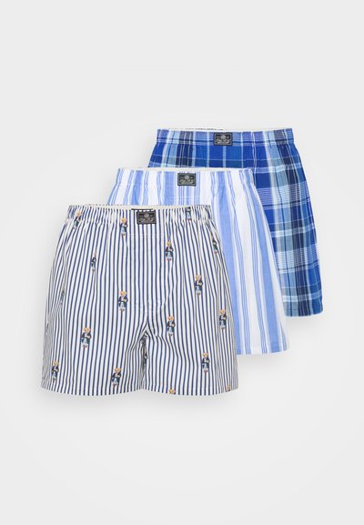 Set de trei boxeri: unul rayat cu un motiv de urs, unul rayat de culoare albastră deschisă și unul cu un model în carouri albastre. Diverse nuanțe de albastru.