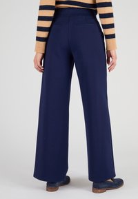 Marineblauwe wijde broek van zachte stof met een gladde textuur, uitgerust met twee achterzakken en een comfortabele tailleband.