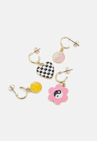 Quatro brincos de argola dourados com pendentes: coração xadrez preto e branco, yin-yang rosa e branco, carinha sorridente amarela, flor rosa com yin-yang preto e branco.