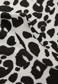 Šedá tkanina s černým leopardím potiskem, obsahující nepravidelné skvrny různých velikostí, hladkou texturu a detail kulatého výstřihu.