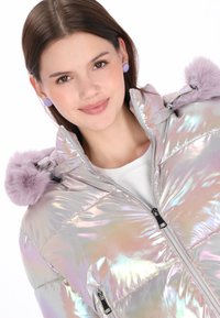 Perłowo błyszcząca puchowa kurtka z wysokim kołnierzem, srebrnym zamkiem błyskawicznym oraz lawendowymi akcentami kaptura z futerka sztucznego. Biała podszewka z kieszeniami zapinanymi na zamek.