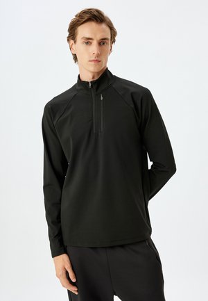 Schwarzer Pullover mit einem Halb-Reißverschluss-Design, gefertigt aus glattem Stoff. Verfügt über Raglanärmel und eine körpernahe Silhouette, die sich gut für Sportbekleidung eignet.