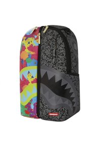 Zaino con un design diviso: un lato presenta un motivo a spruzzo colorato, mentre l'altro è nero con un design di bocca di squalo e dettagli ornamentali.