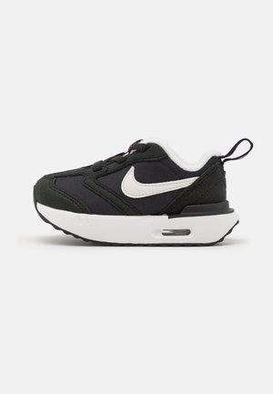 Czarno-białe trampki Nike dla małych dzieci z frontem na sznurowadła, miękką podeszwą i uchwytem na pięcie na białym tle.