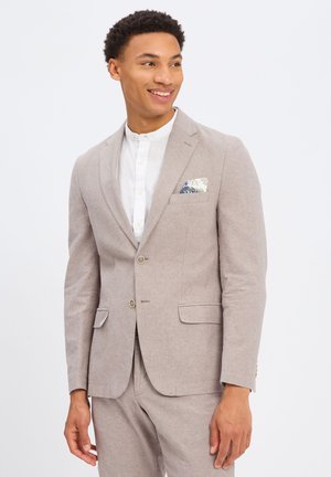 Jasnobrązowy żakiet wykonany z teksturowanej tkaniny, z dwiema przednimi kieszeniami, kieszenią na piersi z kwiatową chusteczką, oraz z dwiema guzikami.