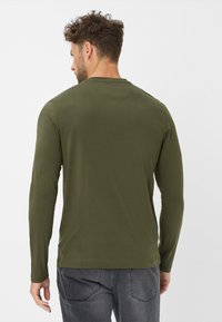 Olivgrünes Langarm-T-Shirt aus glattem Stoff, mit Rundhalsausschnitt und eng anliegenden Ärmeln, sichtbares Markenlogo an der Seite.
