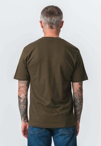 Oliven grøn bomulds T-shirt med korte ærmer, rund hals og en glat tekstur, med et ensfarvet design på bagsiden. Båret med blå denim jeans.