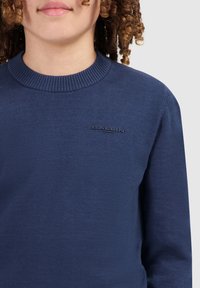 Marineblauer gestrickter Pullover mit einem gerippten Rundhalsausschnitt und einem erhabenen "BALLIN"-Logo auf der Brust, mit einer glatten Textur.