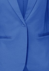 Plavi sako glatke teksture, s jednim gumbom za zatvaranje, reverima s urezom i dva prednja džepa sa suptilnim detaljima tkanja.