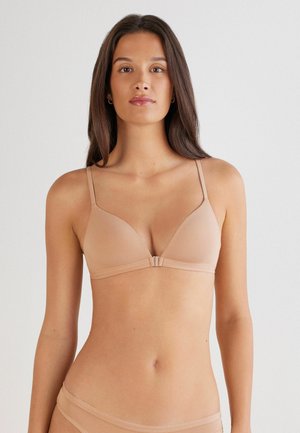 Soutien-gorge sans fil nude avec un tissu lisse, des bonnets triangulaires, des bretelles fines et ajustables, ainsi qu'une fermeture à l'avant. Design simple, sans motifs visibles.