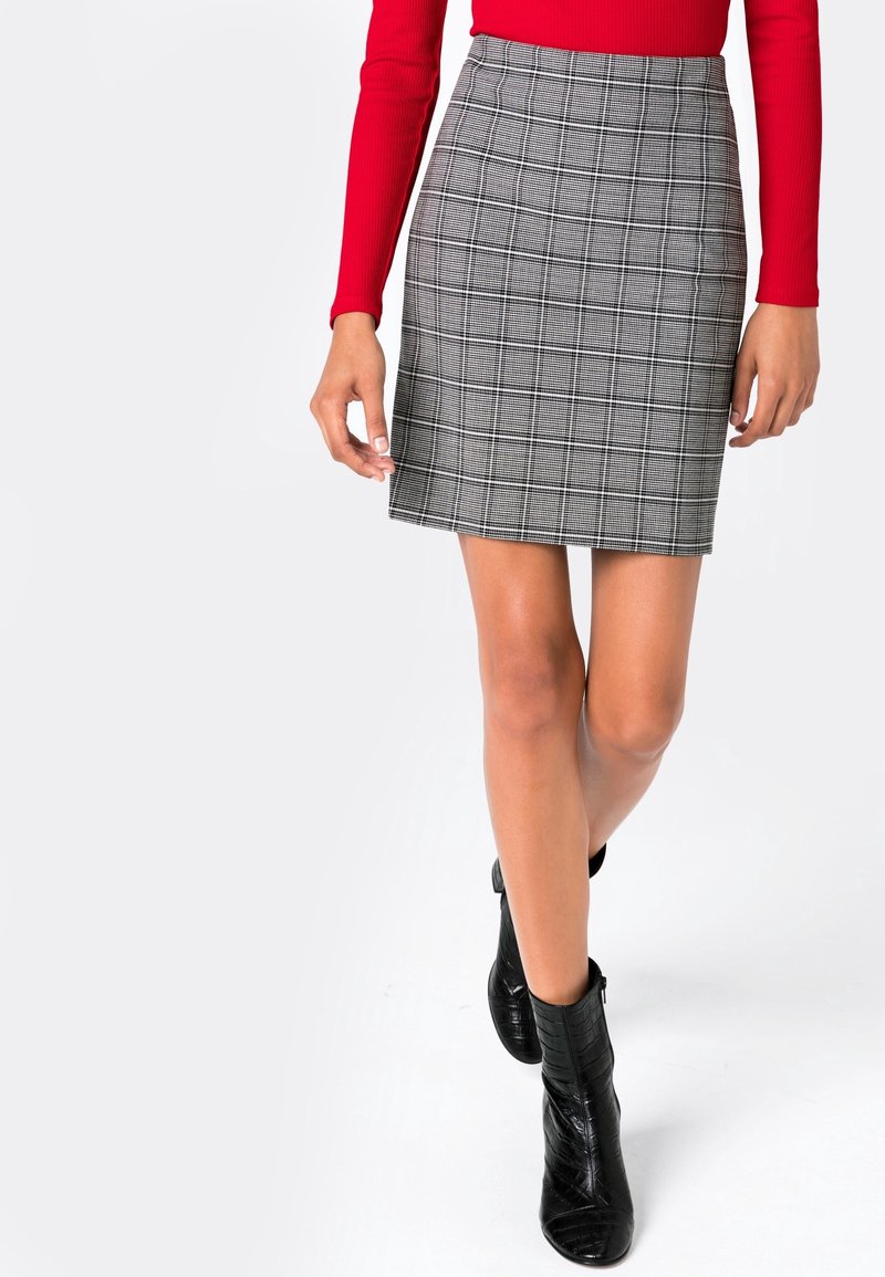 Grå rutiga minikjol med en tight design, med hög midja och subtil textur, i kombination med svarta ankelstövlar.