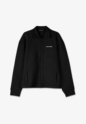 Black button-up jacket made from textured fabric, featuring a collar, long sleeves, side pockets, and a logo on the left side.