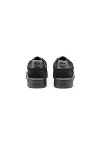Sneakers neri con tomaia in camoscio, dettagli in pelle liscia e suola in gomma spessa con strisce verticali. Logo impresso sul tallone.