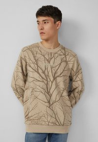 Felpa beige con stampa di rami d'albero marroni, scollo a girocollo a coste e polsini. Mostra il logo "SOLVER" sul davanti.