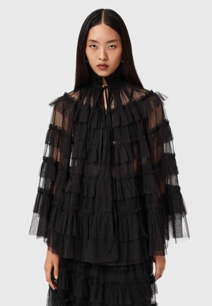 Robe noire transparente avec des volants superposés, des manches longues et un col haut avec un détail à nouer. Texture douce avec une silhouette fluide.