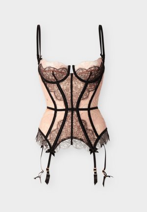 Corset beige avec superposition de dentelle noire, bonnets avec armatures, bretelles réglables et quatre jarretelles noires avec ferrures dorées.