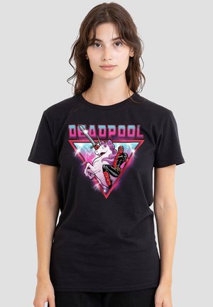 Young woman wearing black T-shirt with colorful Deadpool riding a unicorn graphic and pink lightning in a triangle background.