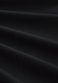 Zwart stof met een gladde, gestructureerde oppervlakte, gekenmerkt door meerdere plooien die een vloeiende uitstraling creëren. Materiaal is ondoorzichtig en duurzaam.