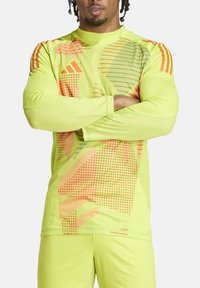 Langarm-Trainingsshirt in fluoreszierendem Gelb mit orangefarbenen grafischen Mustern. Hergestellt aus strukturiertem, feuchtigkeitsableitendem Stoff.