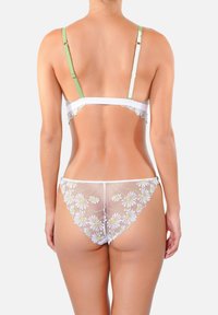 Ensemble de lingerie blanche avec un dos transparent brodé de motifs floraux et des bretelles vertes réglables. Finition en dentelle délicate le long des bordures.