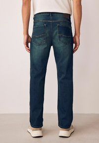 Tumed sinine denimihappe sirgete jalgadega, millel on kaks tagaust ja helepruunid õmblused. Kantakse heledate kingadega.