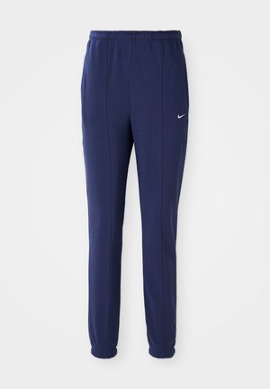 Pantaloni sportivi blu navy con elastico in vita, gambe affusolate e logo Nike bianco sul lato sinistro. Realizzati in tessuto morbido.