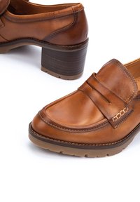 Brown leather loafers with a rounded toe, stacked heel, and decorative stitching on the upper. Smooth texture with contrasting accents.