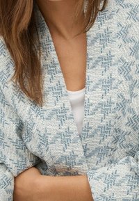 Lekki, teksturowany kardigan w białym i niebieskim kolorze z wzorem w zygzak, szerokimi rękawami i otwartym przodem.