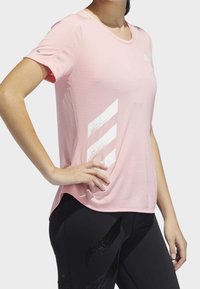 Rosa tränings t-shirt med korta ärmar, med en strukturerad tyg och tre vita diagonala ränder på vänster sida.