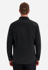 Zwarte langek Mouwen shirt met een kraag en knoopmanchetten, met een gladde textuur en een yoke detail over de rug.