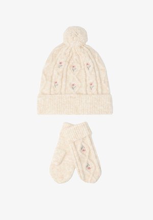 Krémová pletená čepice s bambulí a odpovídajícími rukavicemi, obě s malou výšivkou růžových květin a vroubkovanými manžetami.