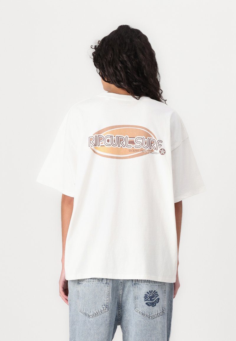 Camisa de t-shirt de gran tamaño en blanco con un gran gráfico en texto naranja y marrón que dice "RIPCURL-SURF" en la parte posterior. Tejido de algodón suave.