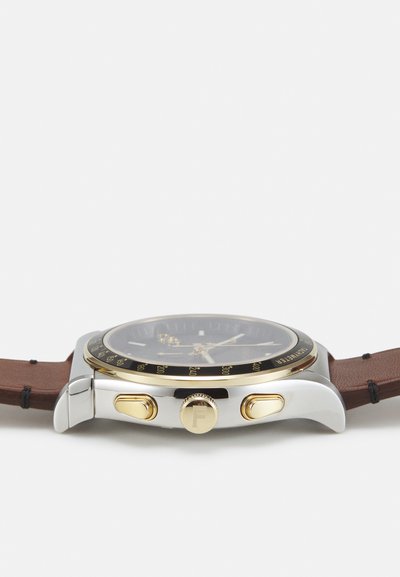 Orologio da uomo con quadrante nero, dettagli in tonalità oro, cassa in acciaio inossidabile argento e cinturino in pelle marrone. Caratterizzato da pulsanti cronografi e indicatori.