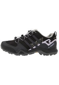 Zapato exterior negro con acentos grises, parte superior de malla y suela de goma. Presenta cordones elásticos, tres rayas en el costado y un talón acolchado.