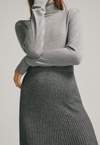 Gray ribbed knit dress with a fitted turtleneck and long sleeves; soft texture, transitioning from smooth top to ribbed skirt.
