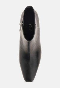 Stivaletto alla caviglia in pelle nera con punta a punta e cerniera laterale. Texture liscia con silhouette elegante e dettagli minimi.