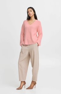 Rosa ribbad stickad tröja med V-ringning, som matchas med beiga skräddarsydda byxor och ljusbruna spetsiga klackar.