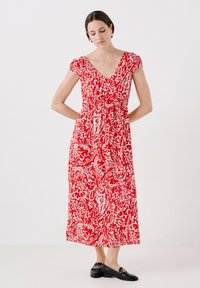 Rode en witte bloemen maxi-jurk met korte mouwen, V-hals, gathered taille en vloeiende rok; gecombineerd met zwarte loafers.