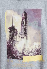 Sudadera gris con un diseño gráfico de un cohete despegando junto a una plataforma de lanzamiento, con texto amarillo en negrita en la parte inferior.