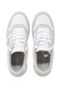 Weiße und hellgraue Sneakers der Marke Guess mit perforiertem Zehenbereich und weißen Schnürsenkeln, von oben auf einem weißen Hintergrund gesehen.