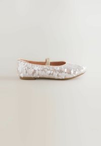 Ballettschuh mit schimmerndem weißen Pailletten-Außenmaterial, beigem Rand und einer runden Zehenpartie. Verfügt über einen Riemen für einen sicheren Sitz.