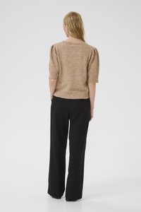 Maglione corto a maniche corte di colore marrone chiaro, con un taglio rilassato e una finitura texturizzata, abbinato a pantaloni neri larghi.