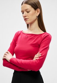 Majica dolgimi rokavi s kroglastim izrezom v svetlo roza barvi iz bombaža, ki ima majhen logotip na prsih in prilegajoč kroj.