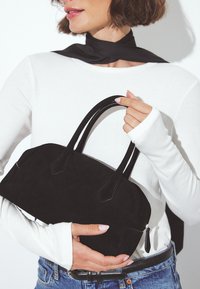 Melnas zamša rokassomas ar noapaļotu formu, elegantu dizainu un īsām rokturiem. Iespējo neliels rāvējslēdzēja vilkšanas elements aizvēršanai un gluda virsma.